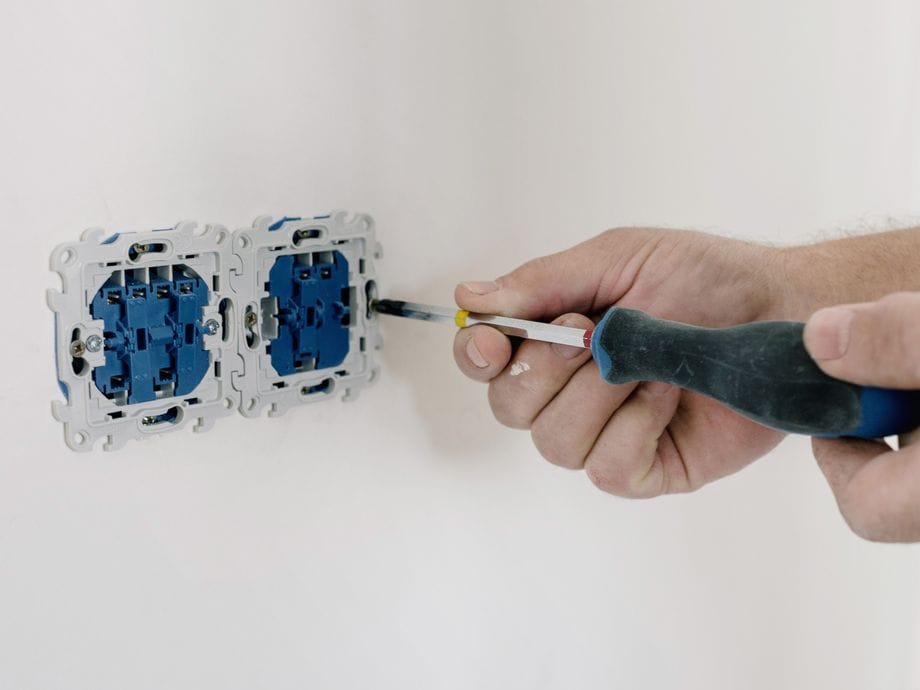 Electrician diagnosing a faulty socket circuit with a screwdriver